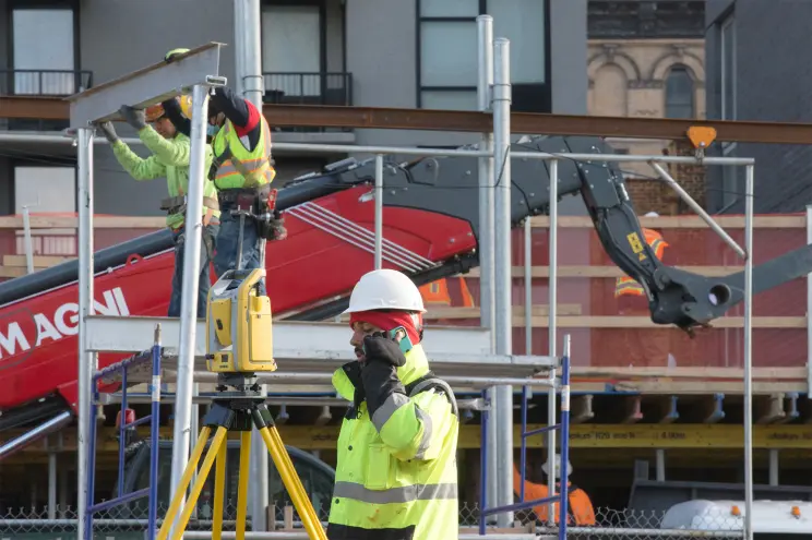 Group of diverse construction workers in hard hats and safety vests, working on a job site.